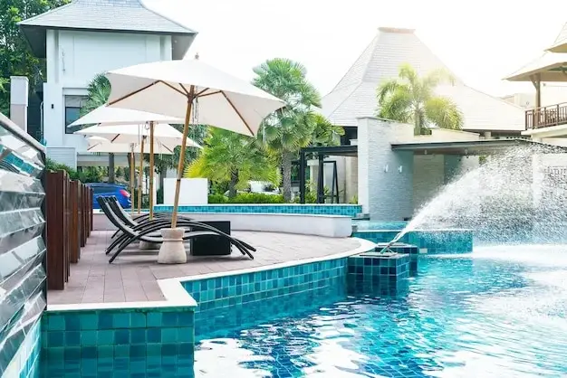 Custom pool with a raised teal tile spa wall and arcing water jets spilling into the pool