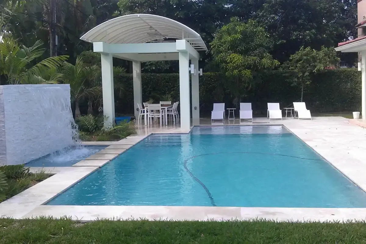 Rectangular pool with a white domed pavilion, lounge chairs and a paver deck
