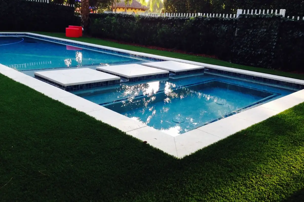 Rectangular pool with a tanning ledge and a partly drawn safety cover on a lawn