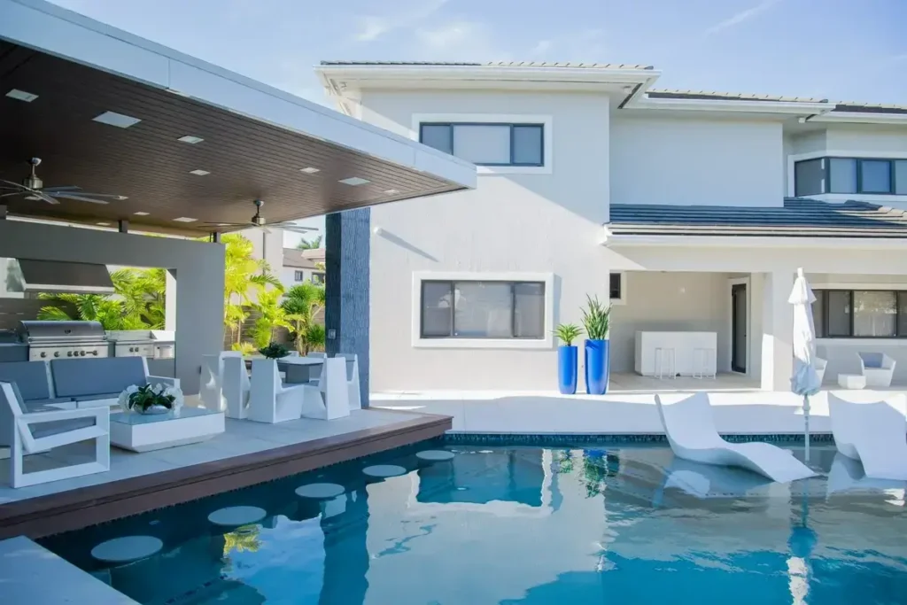 Pool with an in-water lounge shelf and blue planters beside modern patio