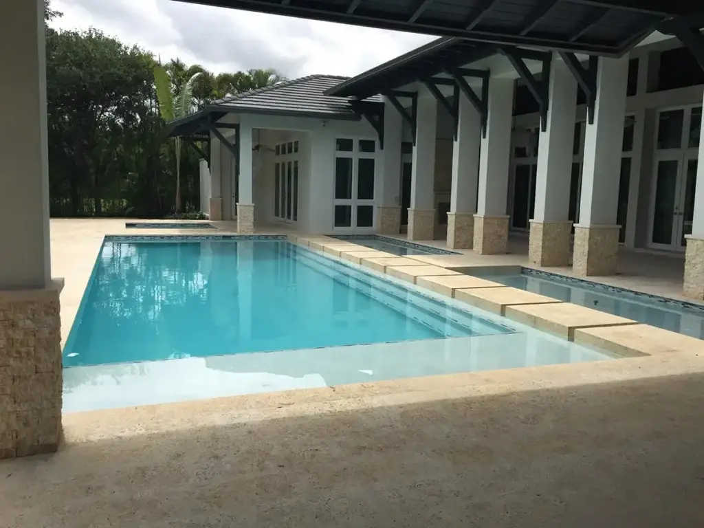 Rectangular lap pool beside a columned covered patio
