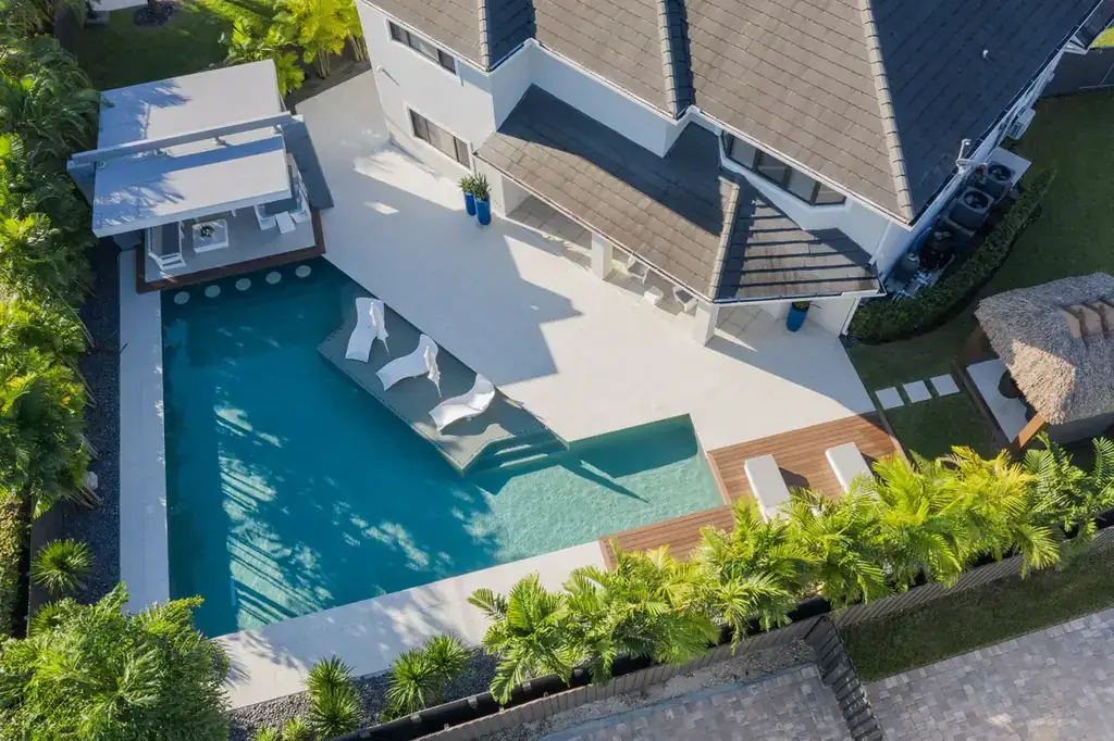 Rectangular pool with a sun shelf and lounge chairs beside a covered patio