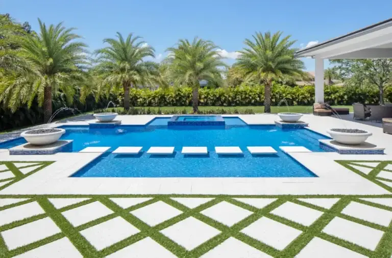 Resort style pool with in water loungers, palm rows and a chequerboard lawn and paver deck